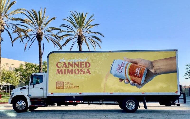 Ohza box truck wrapped with 'the original canned mimosa' and a hand holding a can of Classic Mimosa